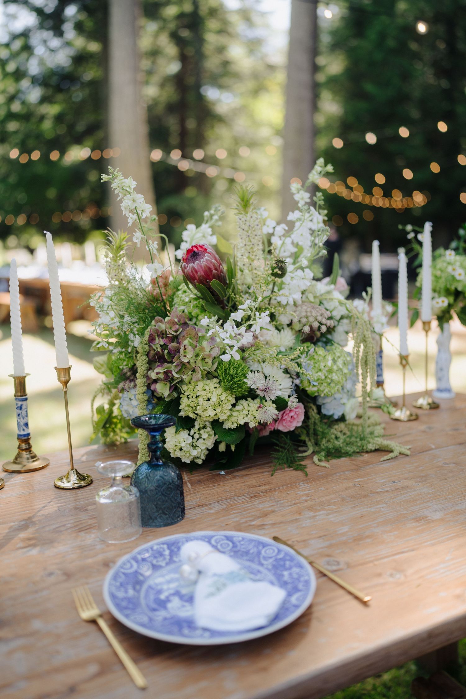 Elegant wedding table decorated with white hydrangeas, candles and blue china plates.