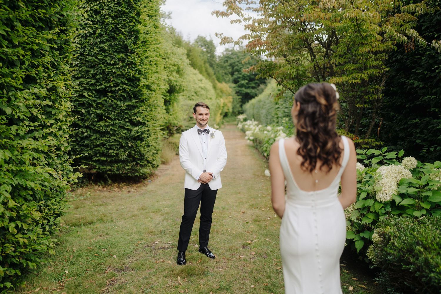 Couple shares intimate moment on garden path surrounded by lush greenery.
