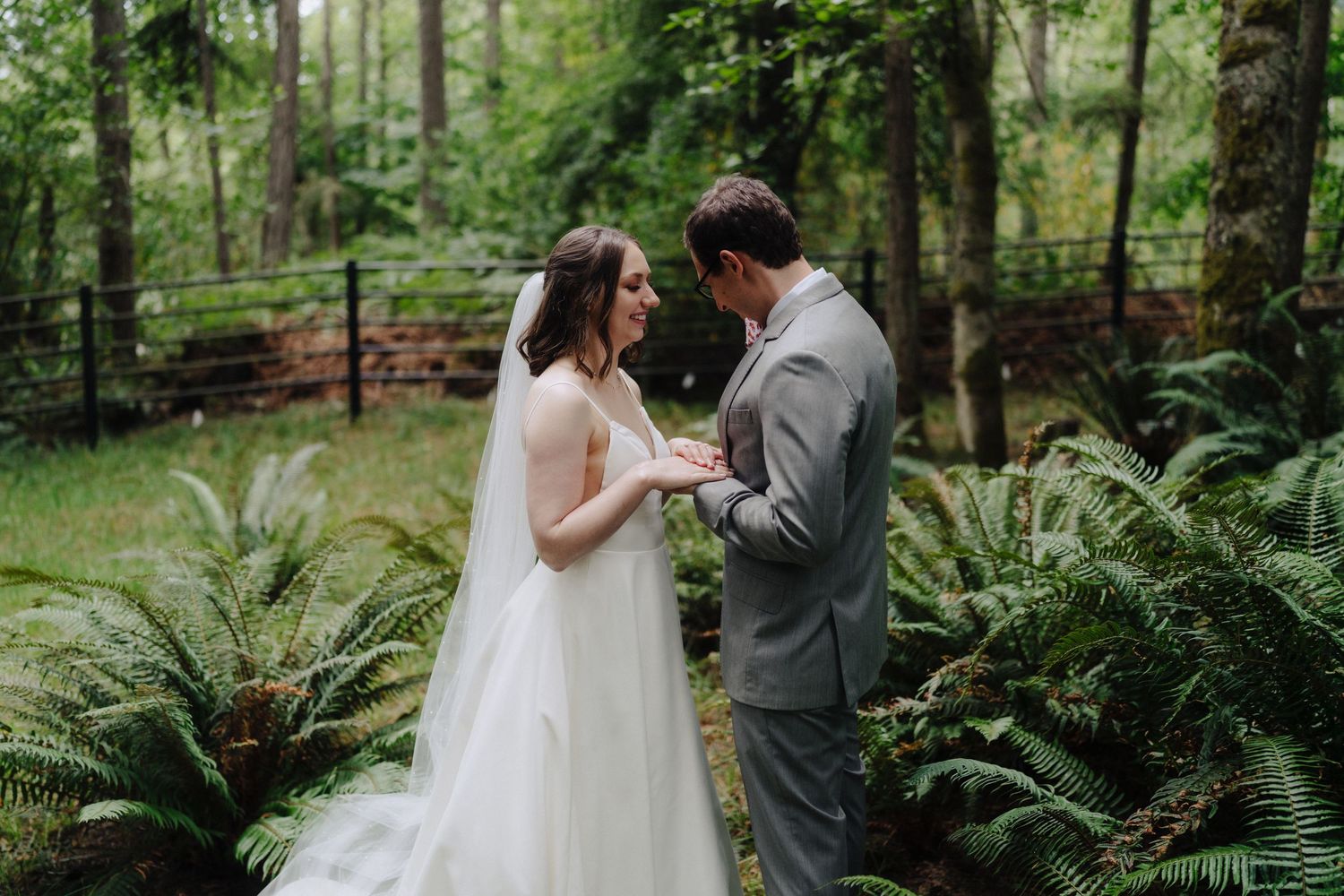 Romantic wedding couple moment among ferns in forest setting.
