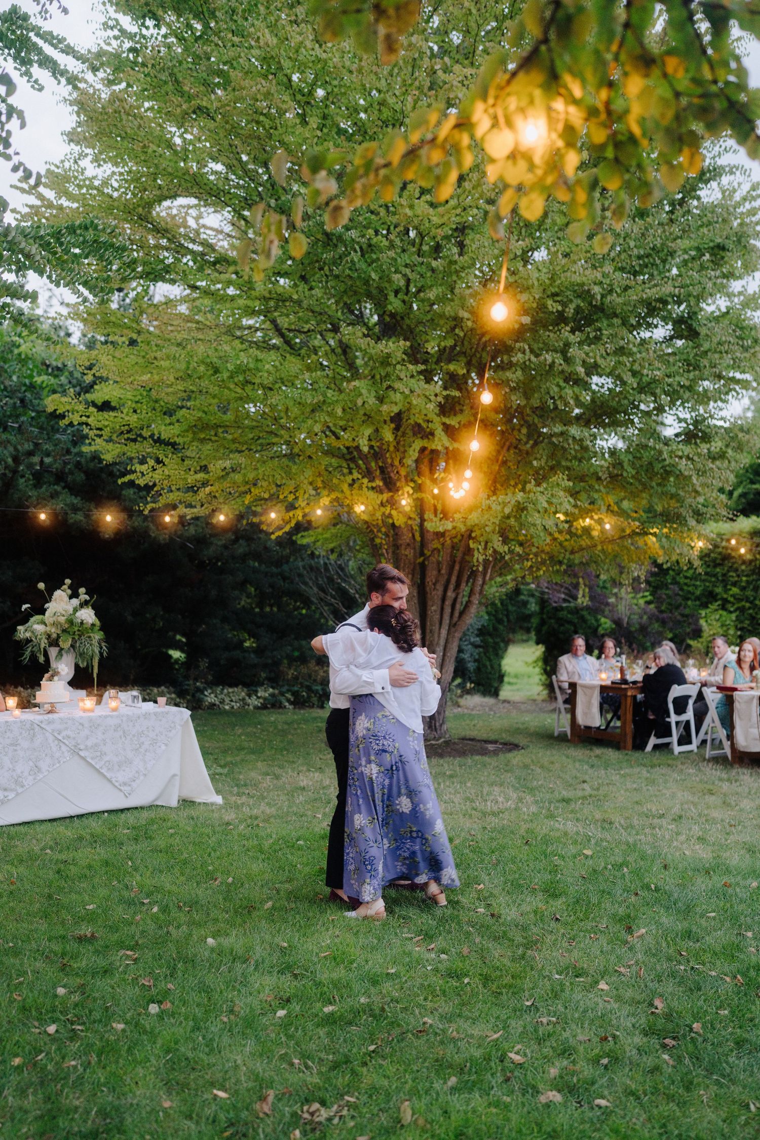 Couples dancing on a grassy lawn during an outdoor evening wedding reception.
