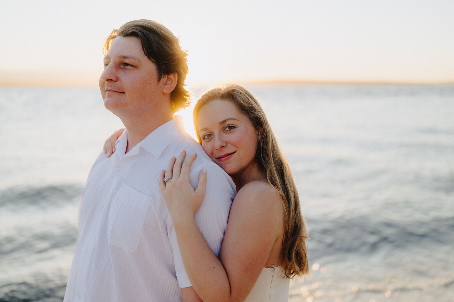Couple sharing an intimate moment on the beach during golden hour.