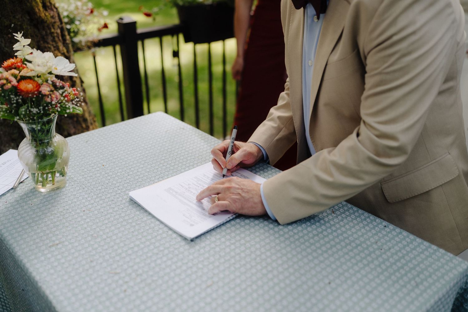 Someone signing the wedding guest book at an outdoor reception.