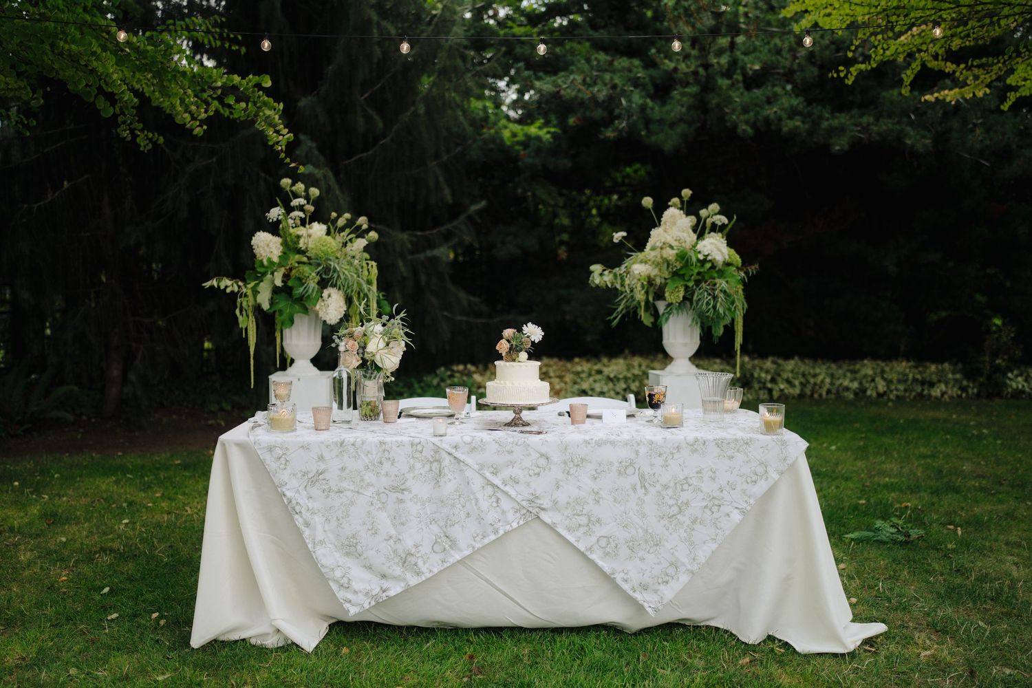 Elegant white reception table with floral centerpieces and formal place settings.