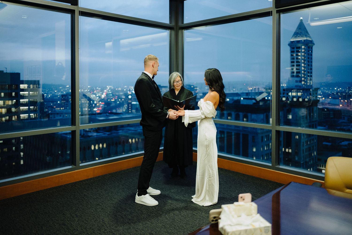 A couple exchanges vows during their intimate rooftop wedding ceremony with city skyline views.