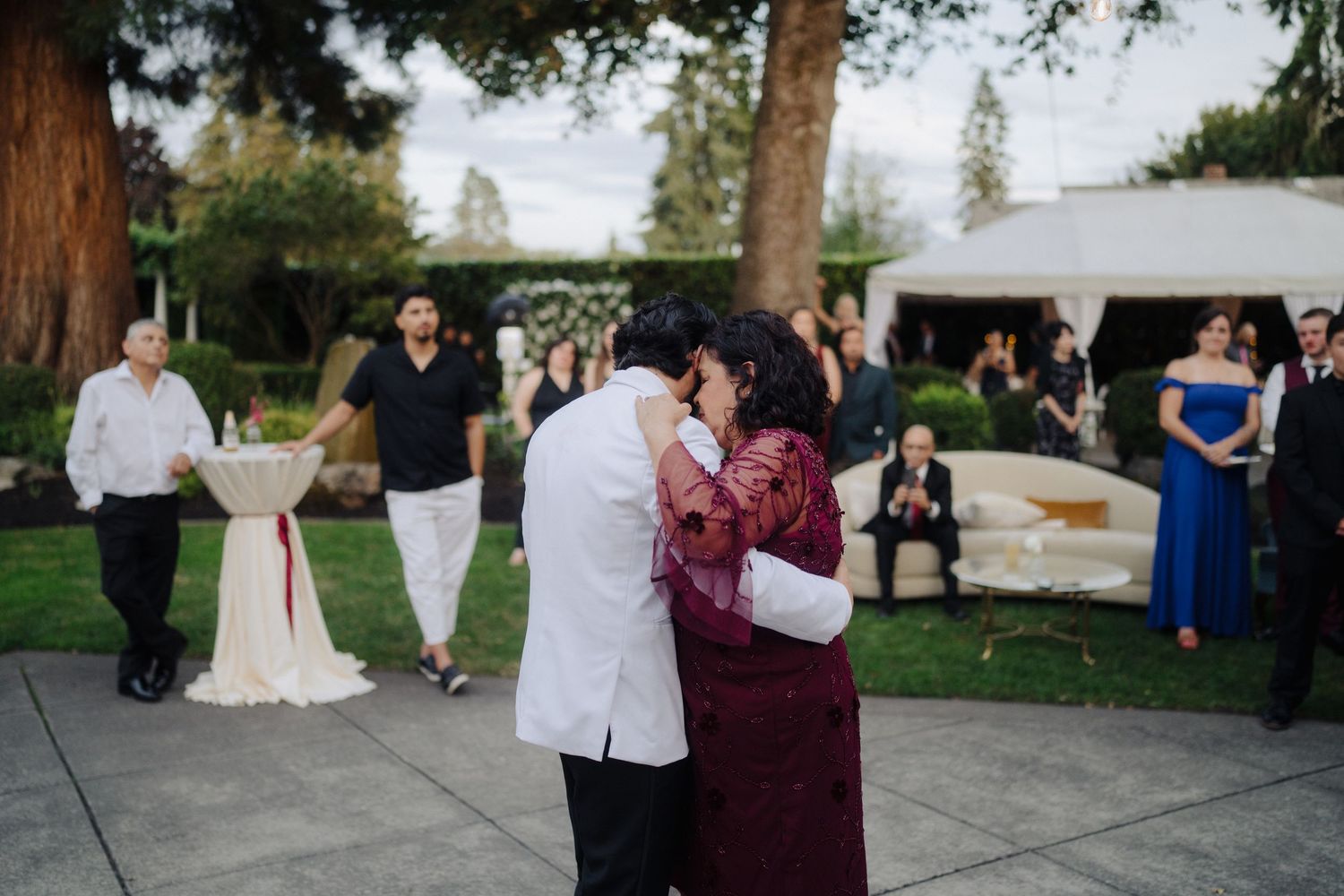 Wedding party members dance and celebrate on an outdoor patio during the reception.