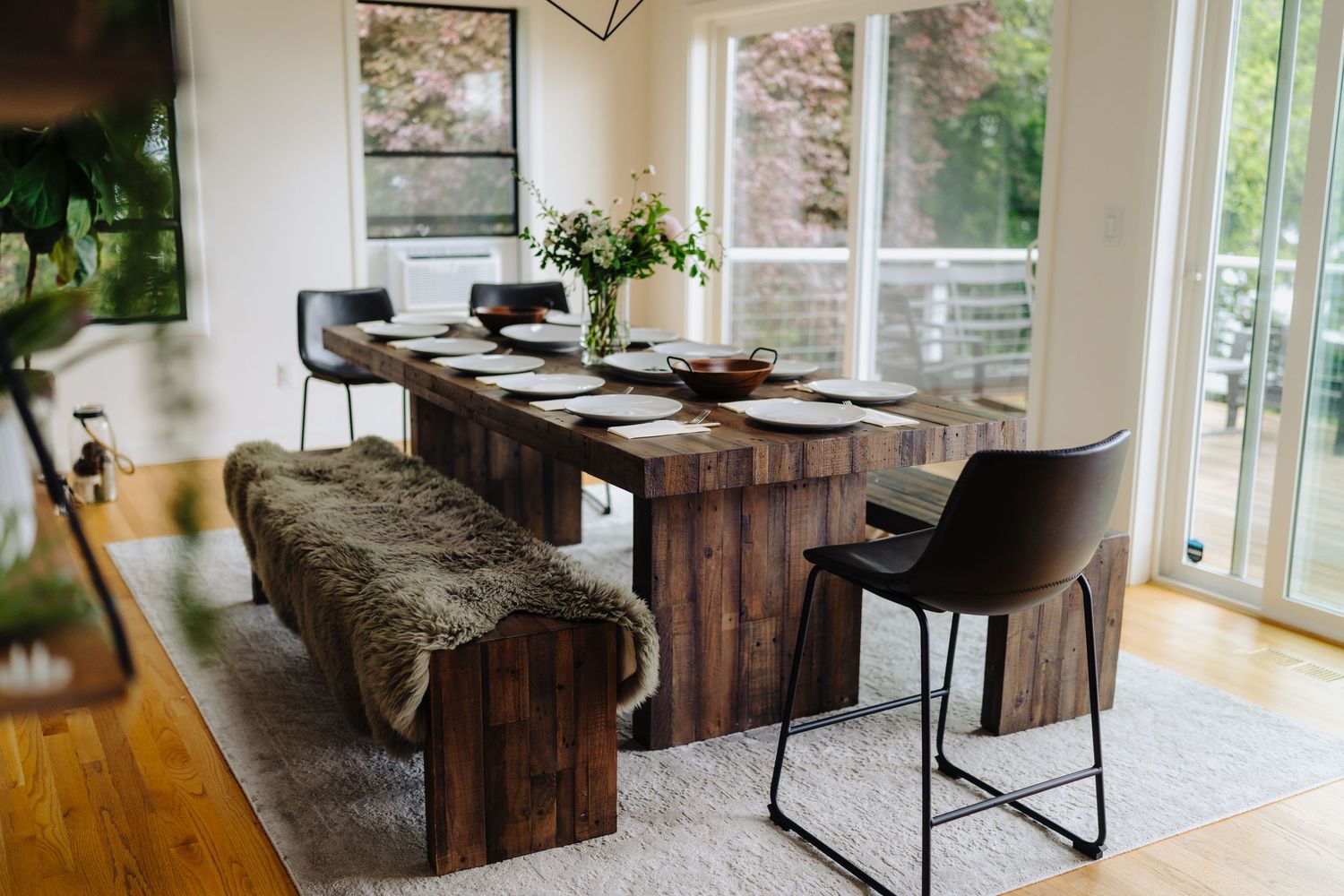 Modern office interior with wooden furniture and large windows letting in natural light.