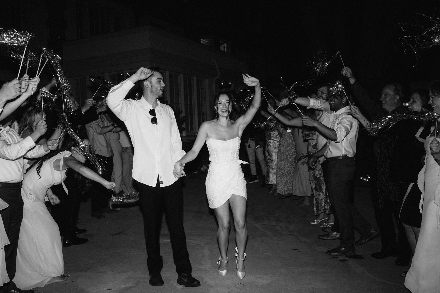 Wedding party dancing in a line during an evening outdoor celebration.