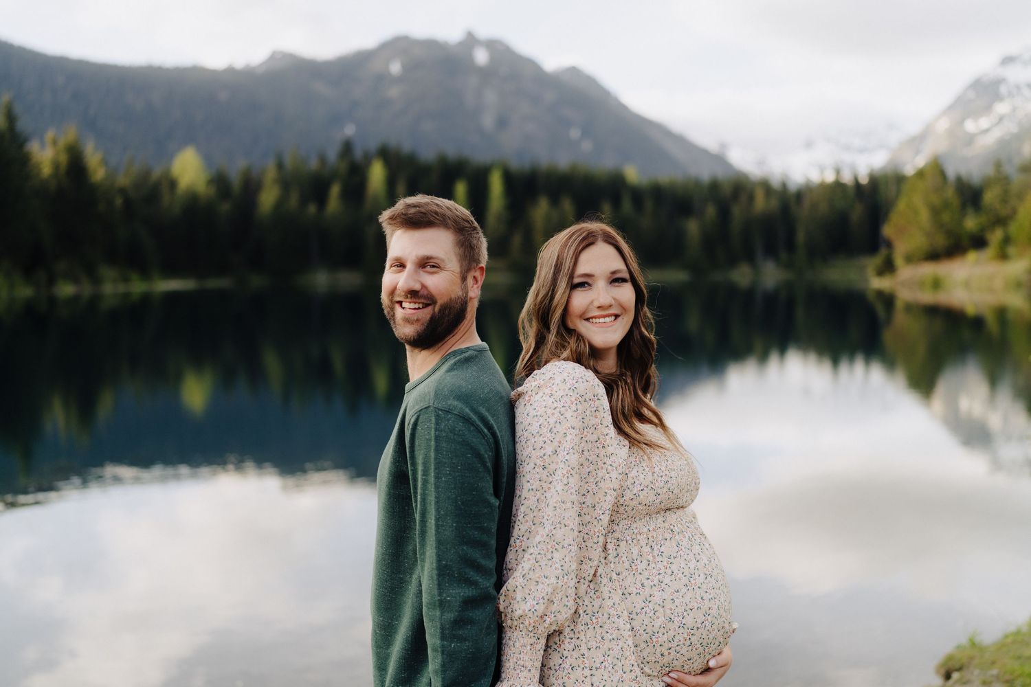 Couple shares romantic moments by a serene mountain lake surrounded by evergreen forest and misty peaks.