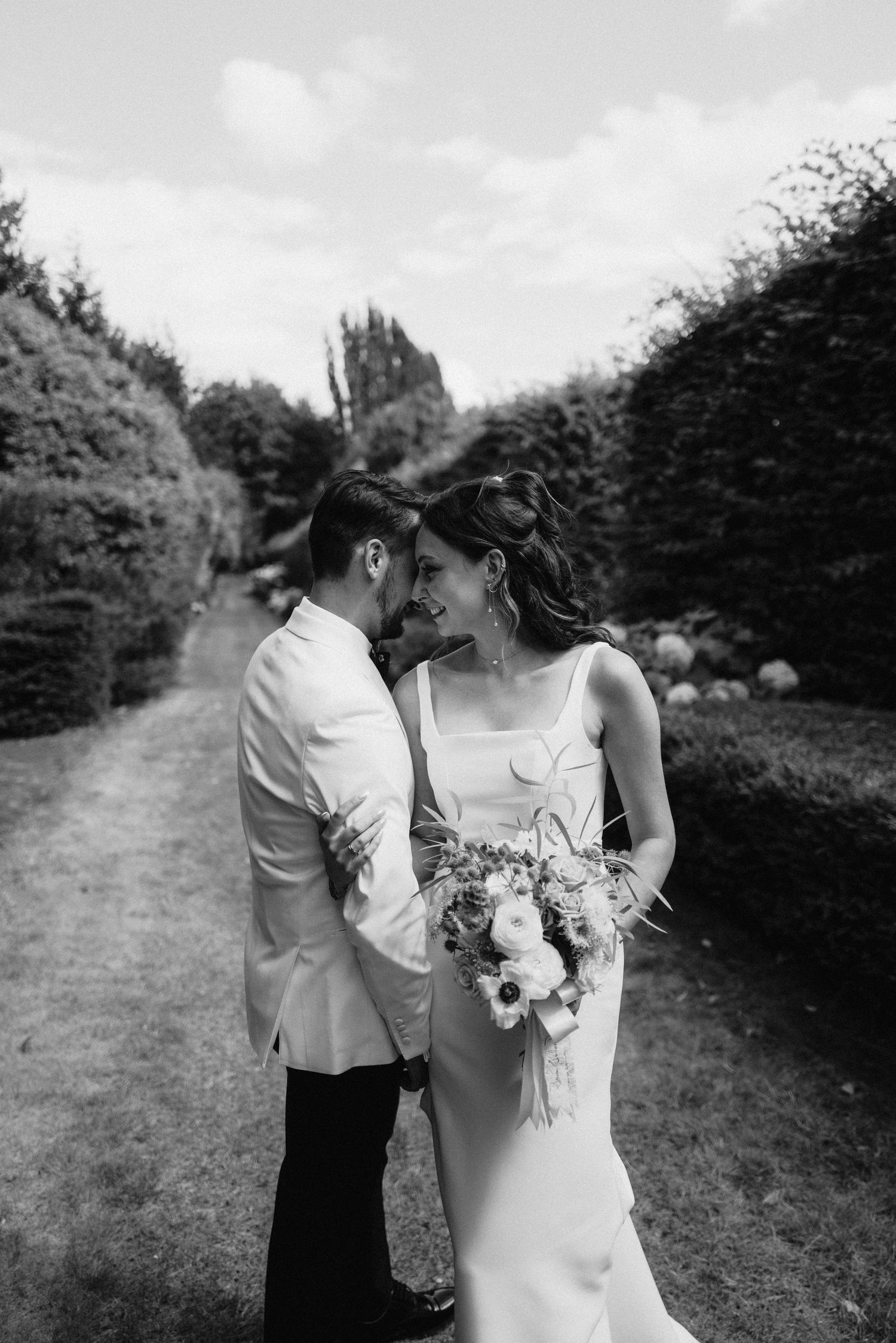 Black and white romantic garden wedding photo with elegant floral bouquet.