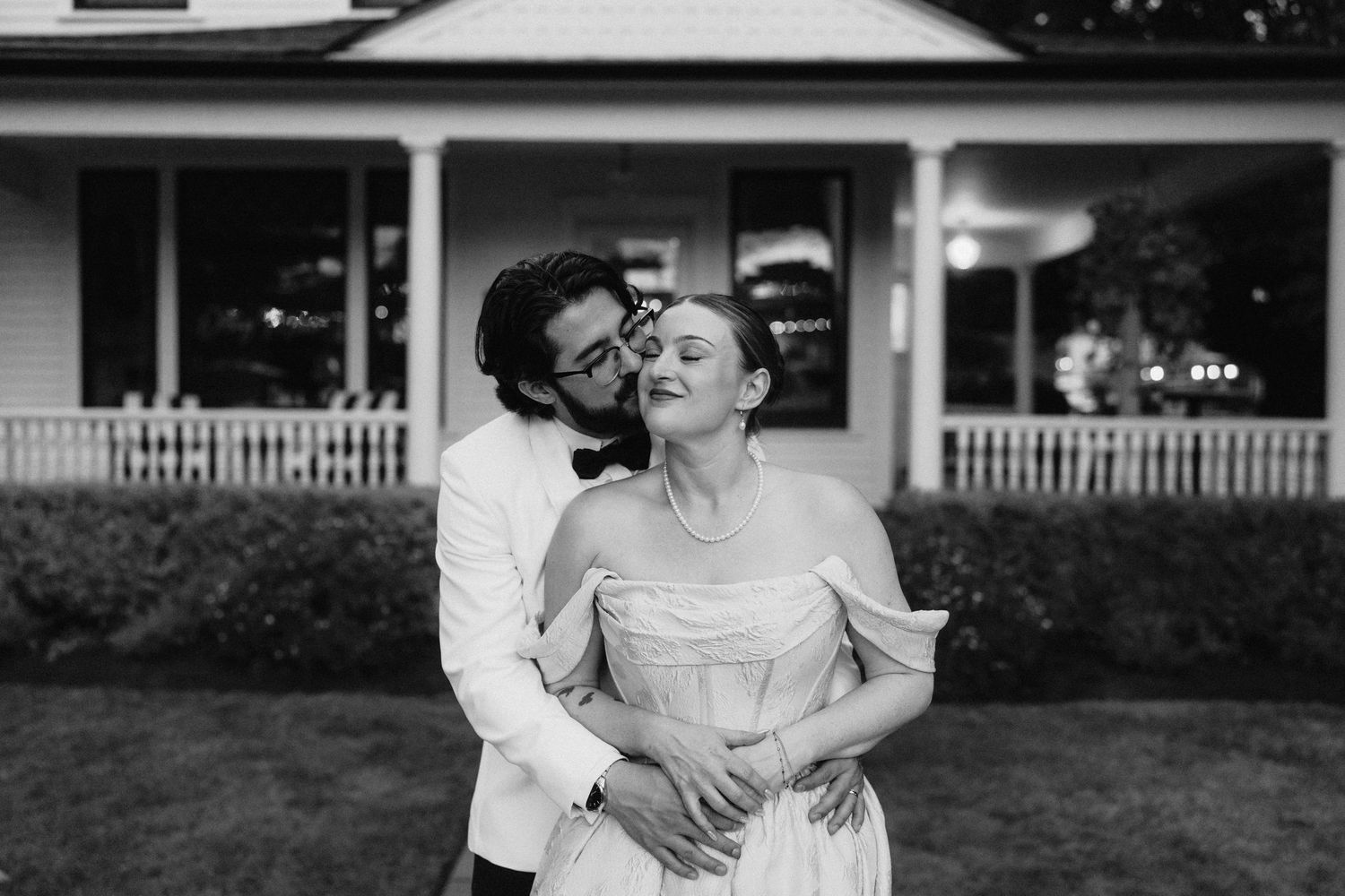 Classic white farmhouse style venue with wrap-around porch and elegant columns.