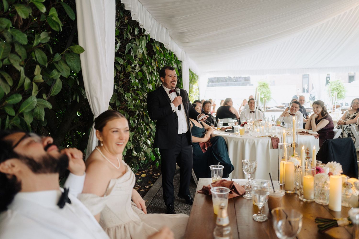 Wedding reception dining area with white draping, green walls and ambient candlelight.