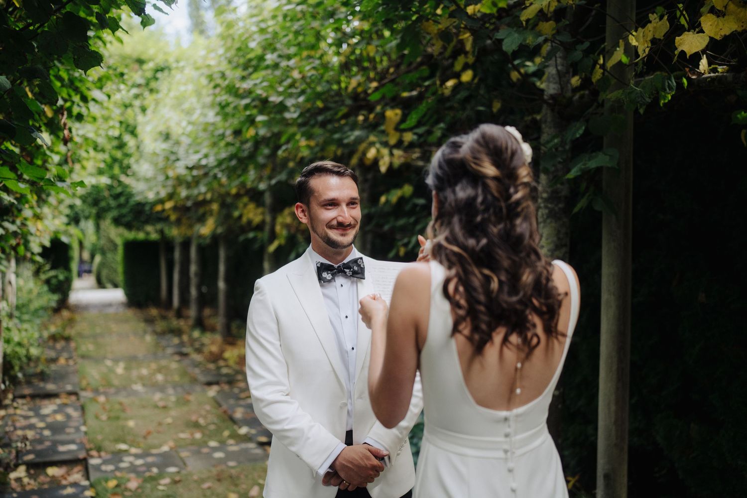 A couple shares laughter during their first look wedding moment in a scenic forest setting.