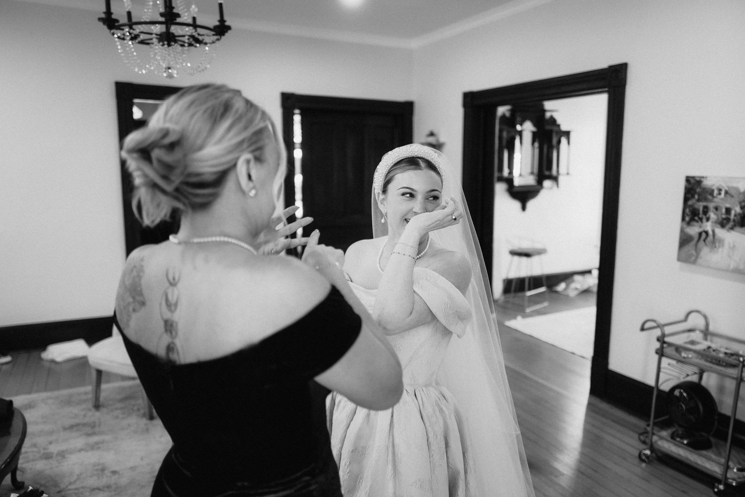 A tender moment captured in black and white as wedding preparations take place in an elegant room.