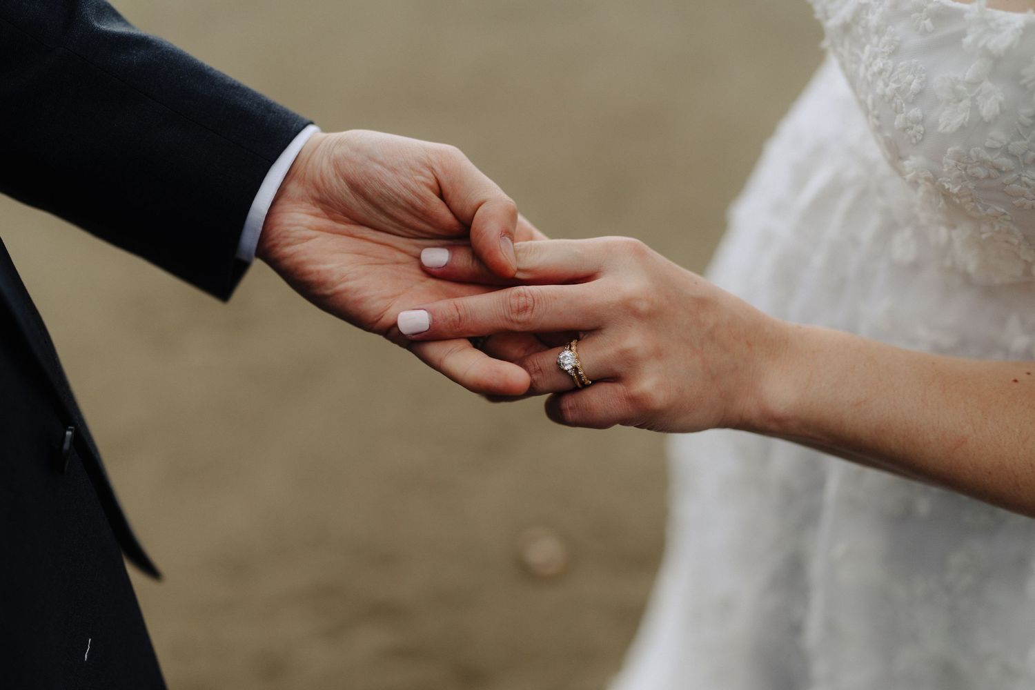 Close-up of hands exchanging rings during beach wedding ceremony.