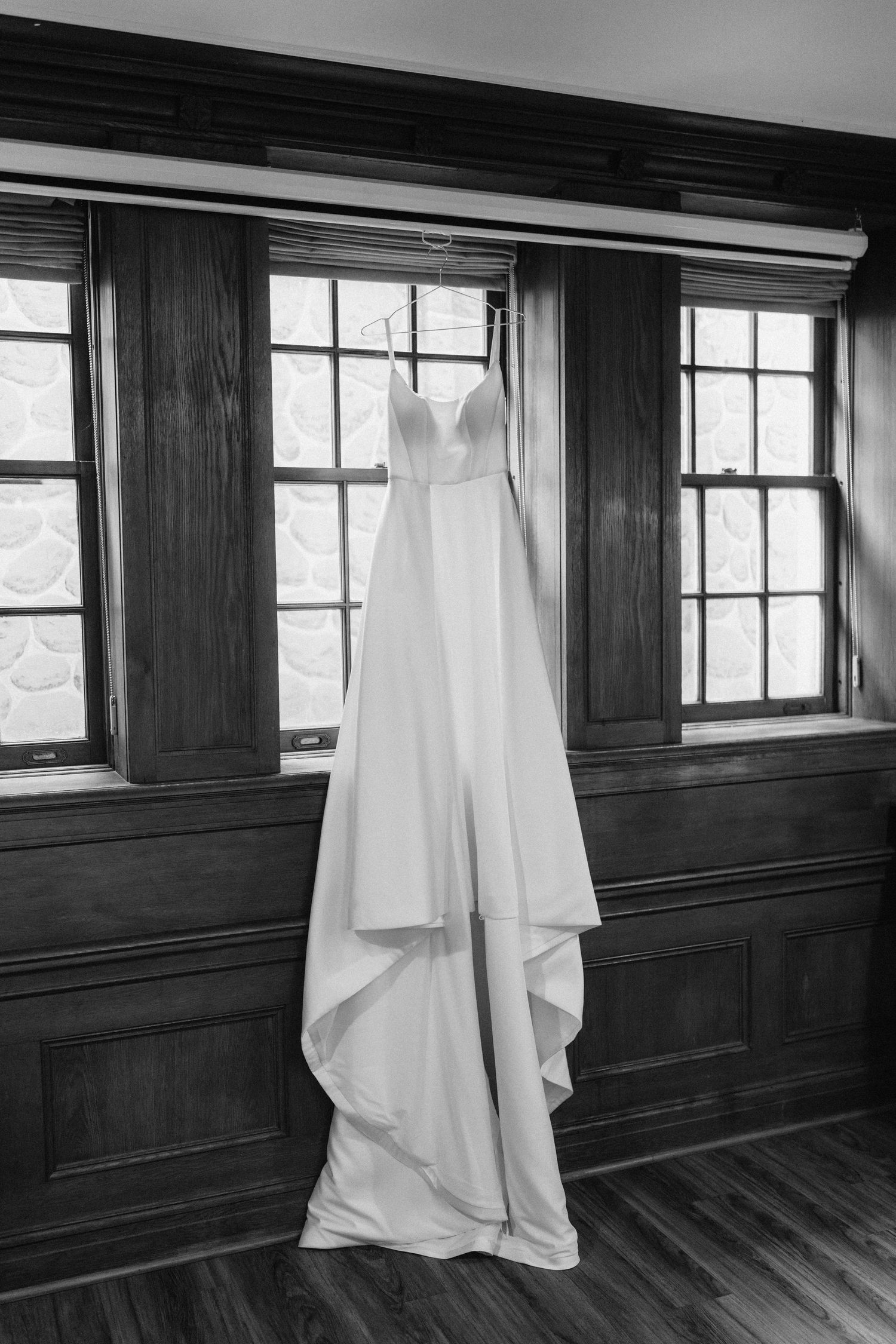 Black and white photo series showing white sheets hanging in a dark wood-paneled room with windows.