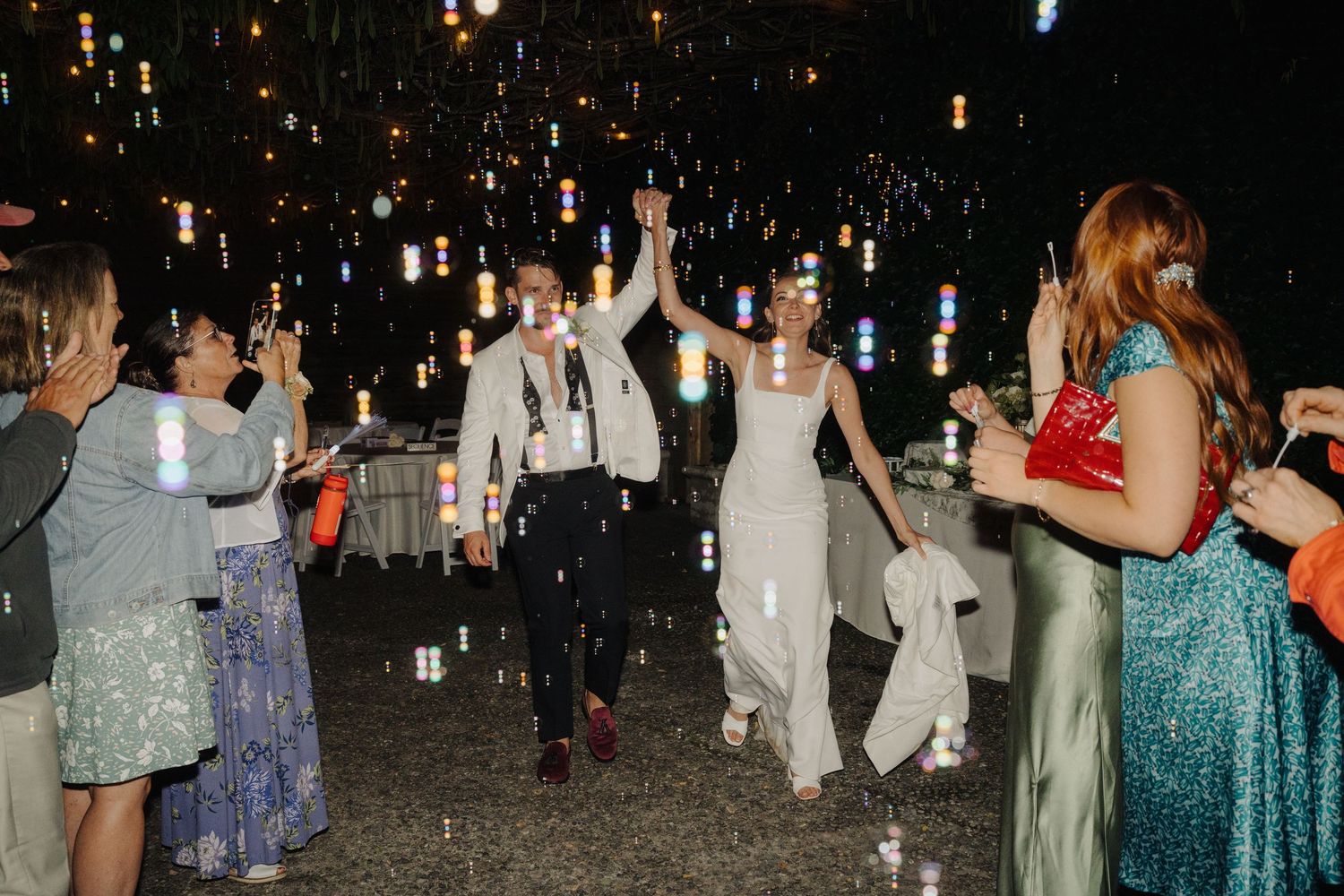 Evening wedding reception celebration with hanging lights creating a magical atmosphere.