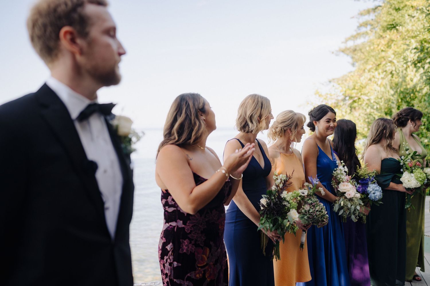 Wedding guests gather outdoors in formal attire during a sunny daytime celebration.