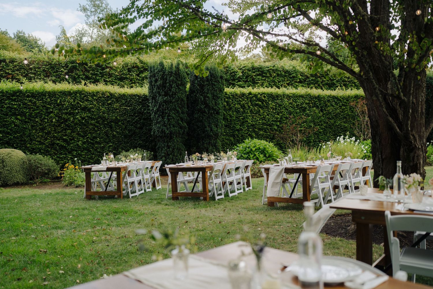 White folding chairs arranged in rows for an outdoor garden wedding ceremony.