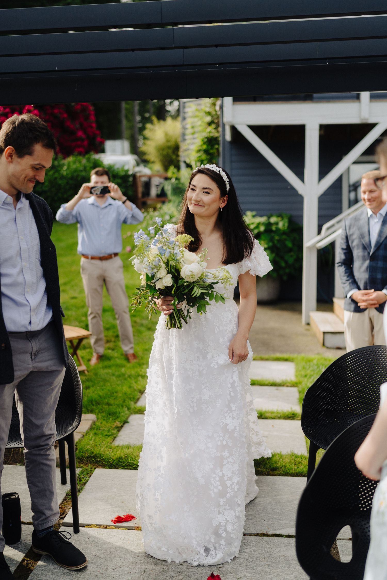 Wedding ceremony setup with white chairs and decorations in an outdoor garden venue.