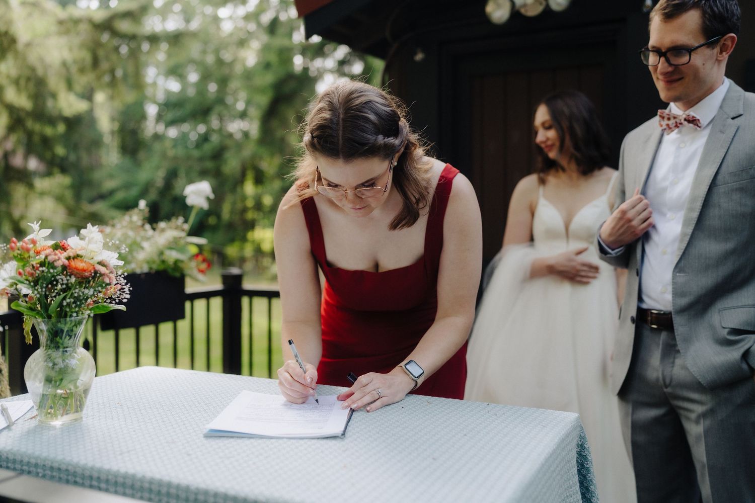 Wedding ceremony signing table set up outdoors with guests watching the proceedings.