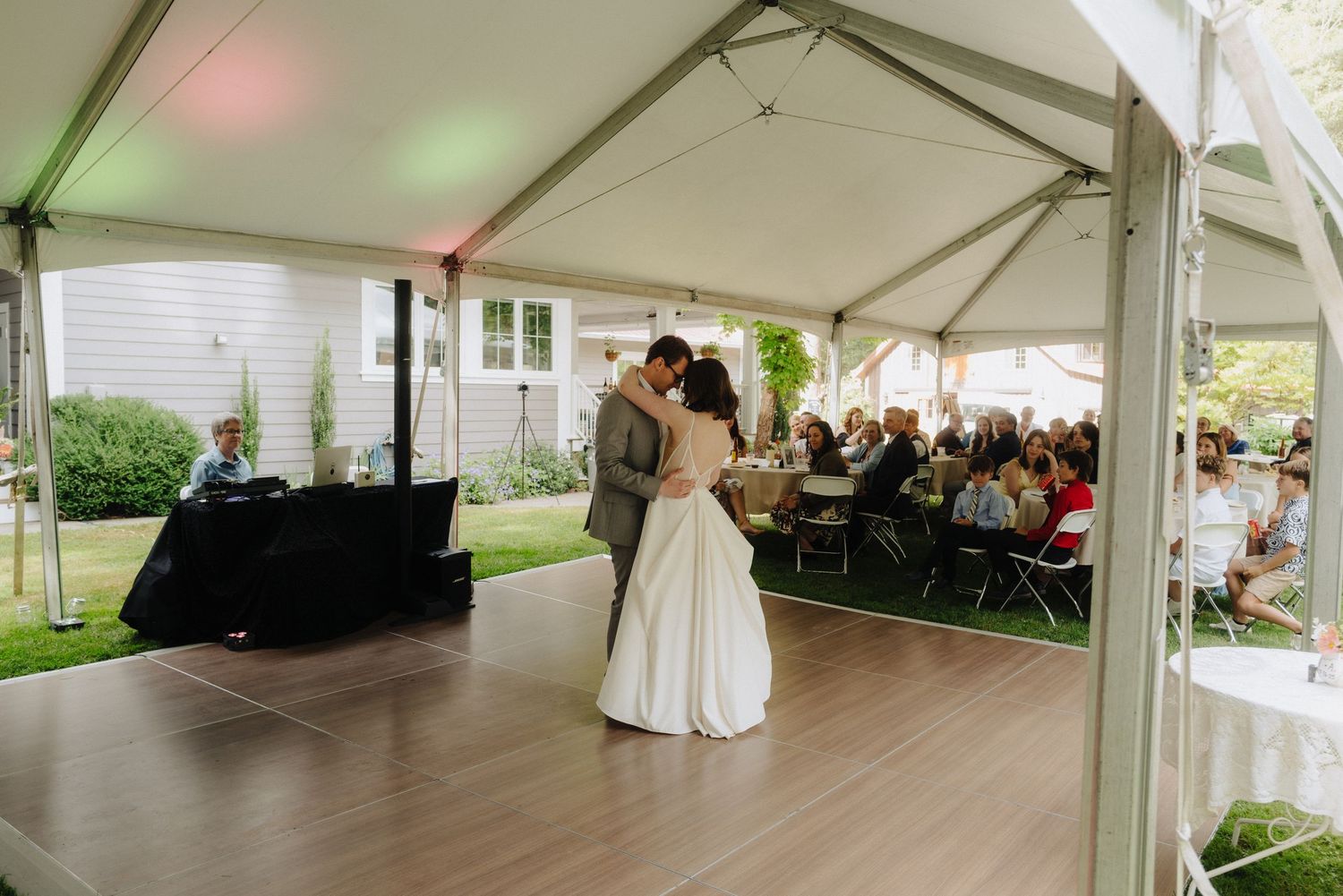 Large white wedding reception tent with dance floor and guest seating.