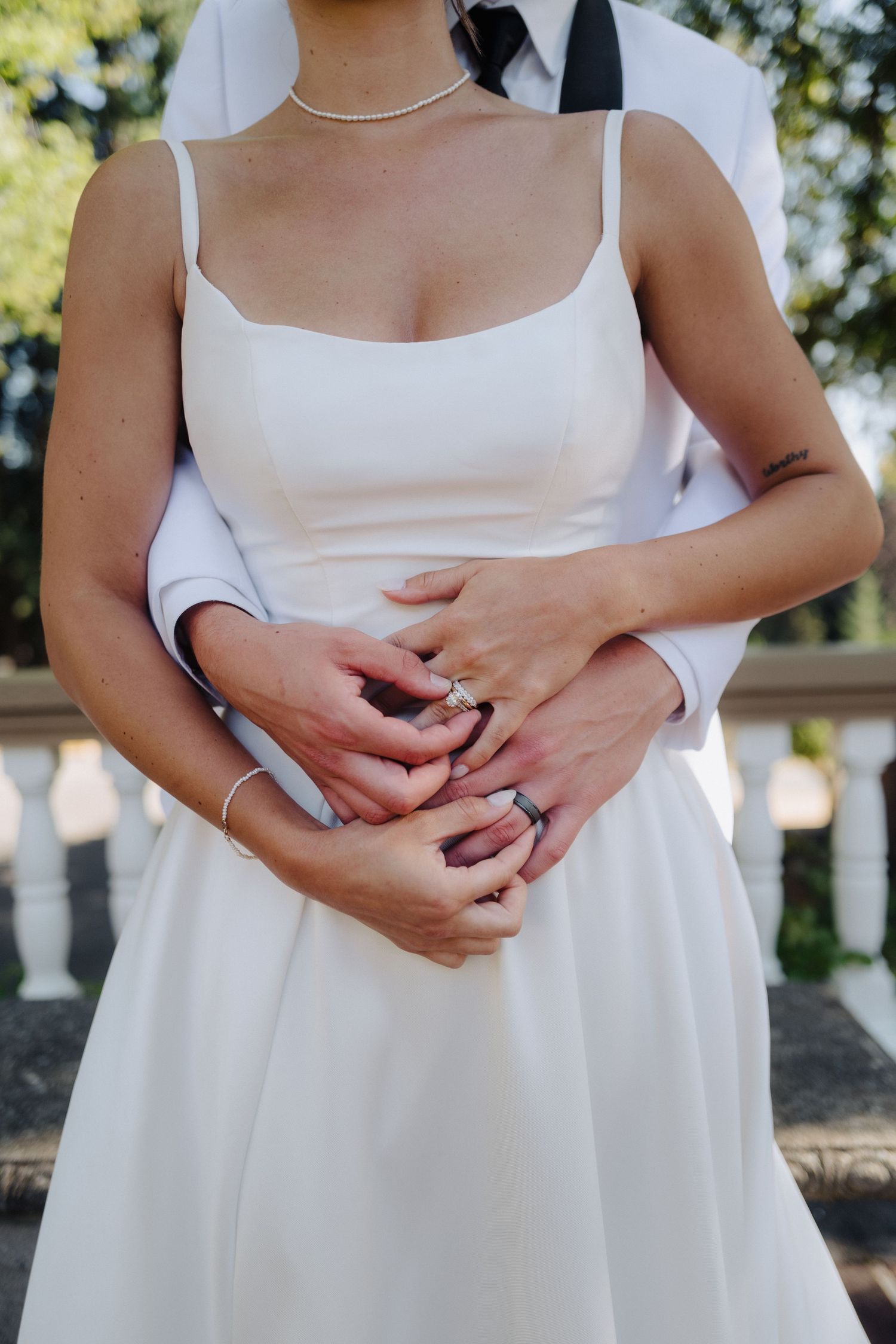 Close-up details of white wedding dresses and clasped hands during a celebration.