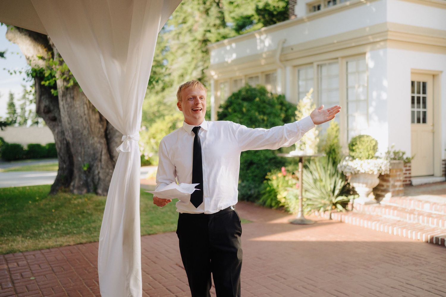 A couple shares their first dance moment under an elegant white tent at their garden wedding reception.