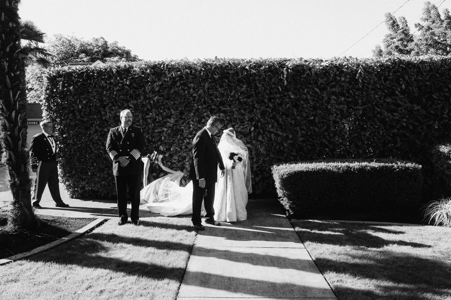 Black and white photo of wedding guests walking along a garden path.