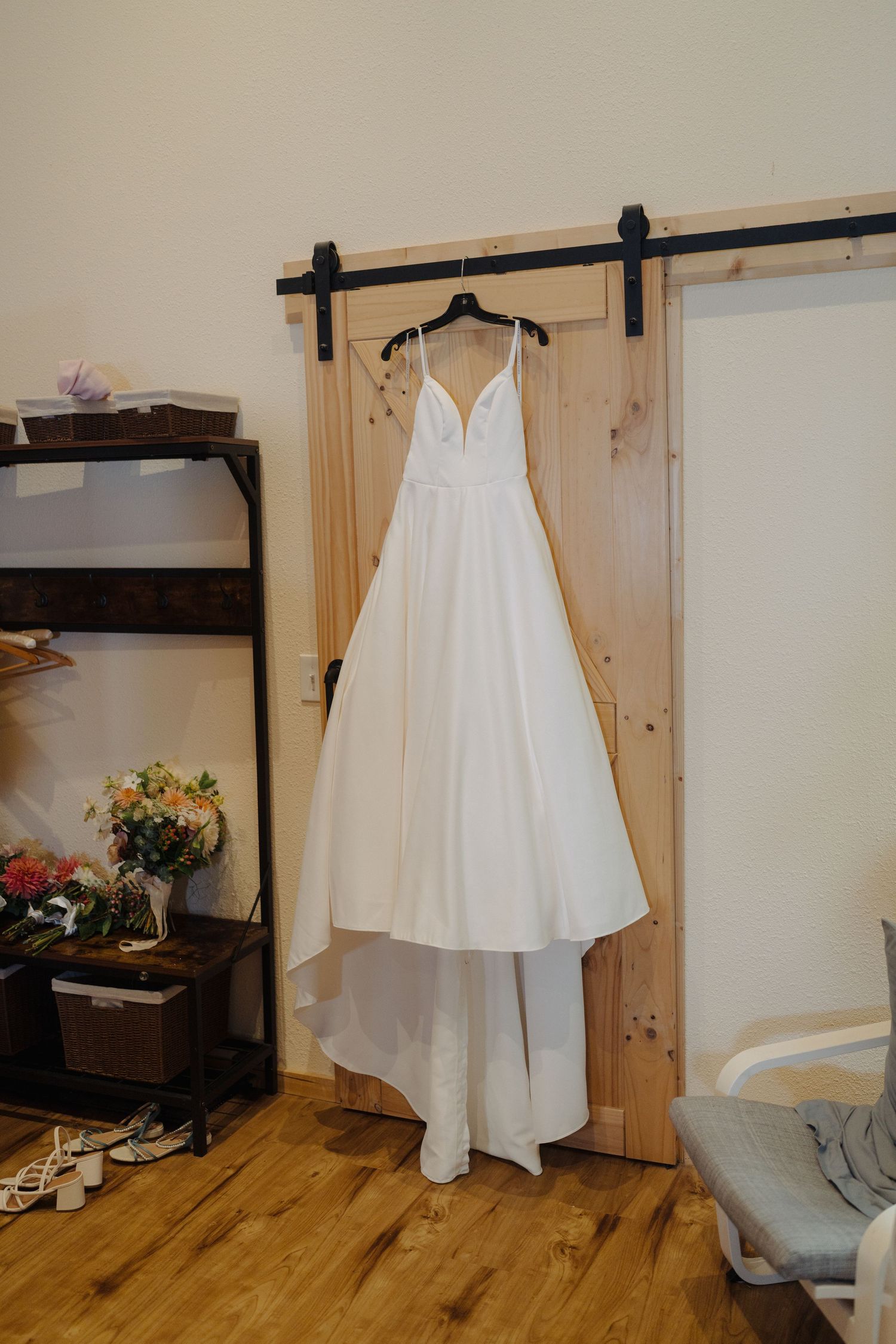 White wedding dress hanging on wooden wall displays in rustic indoor setting.