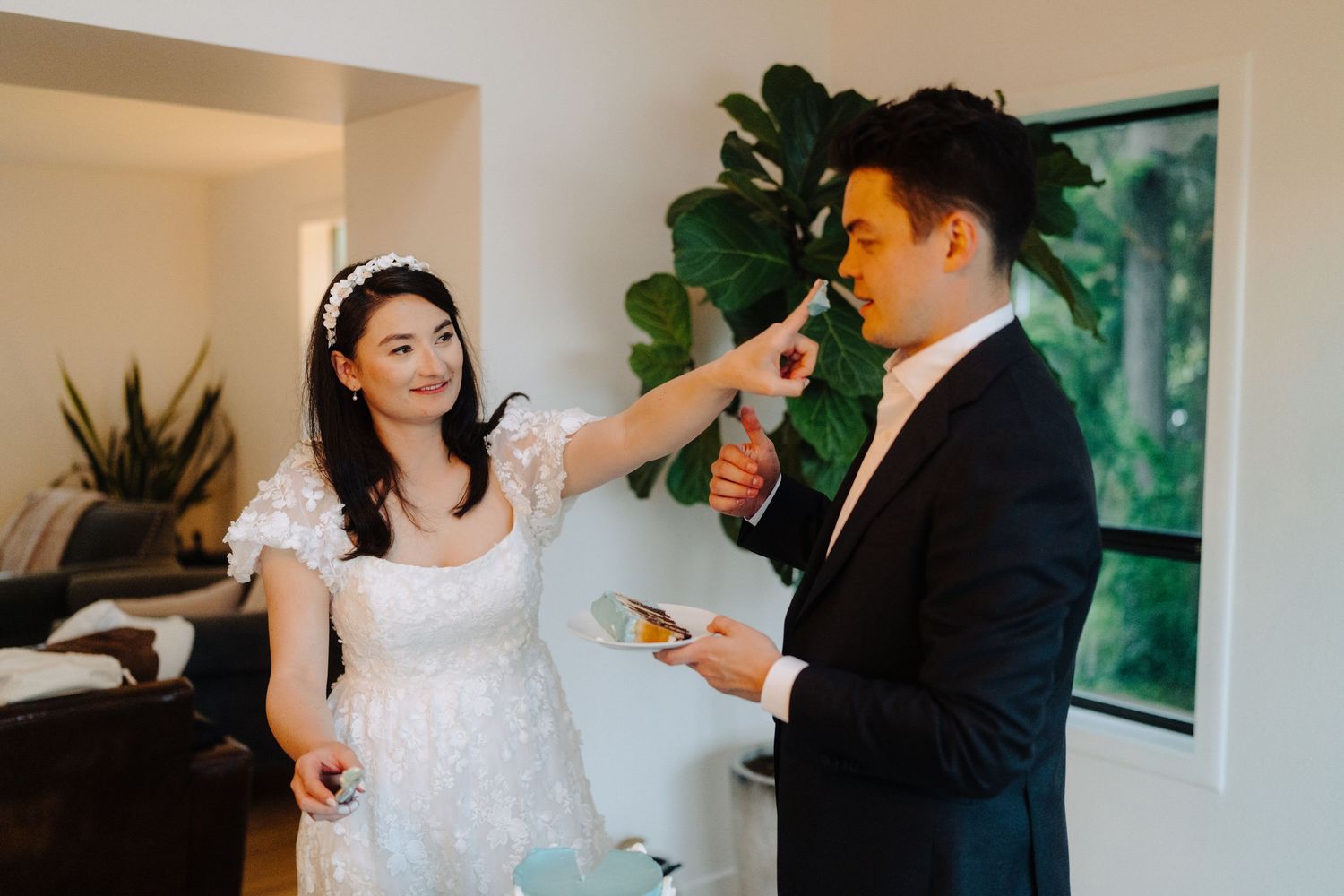 Couple sharing cake and laughing together during their wedding reception.