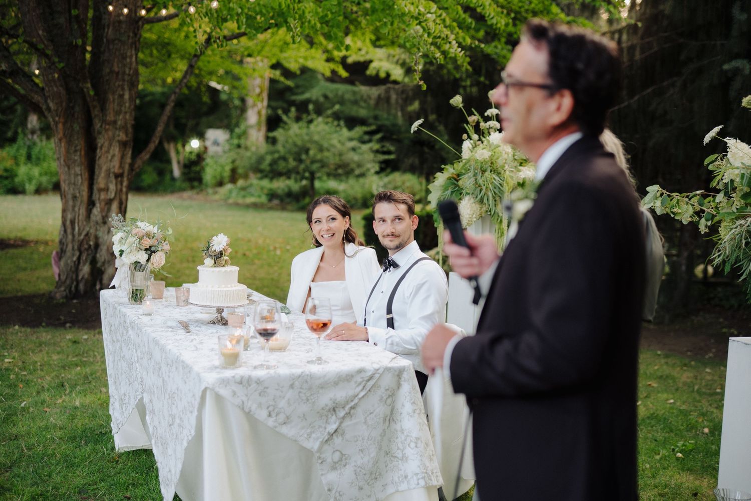 Outdoor wedding reception with white-clothed tables set up on a lawn.