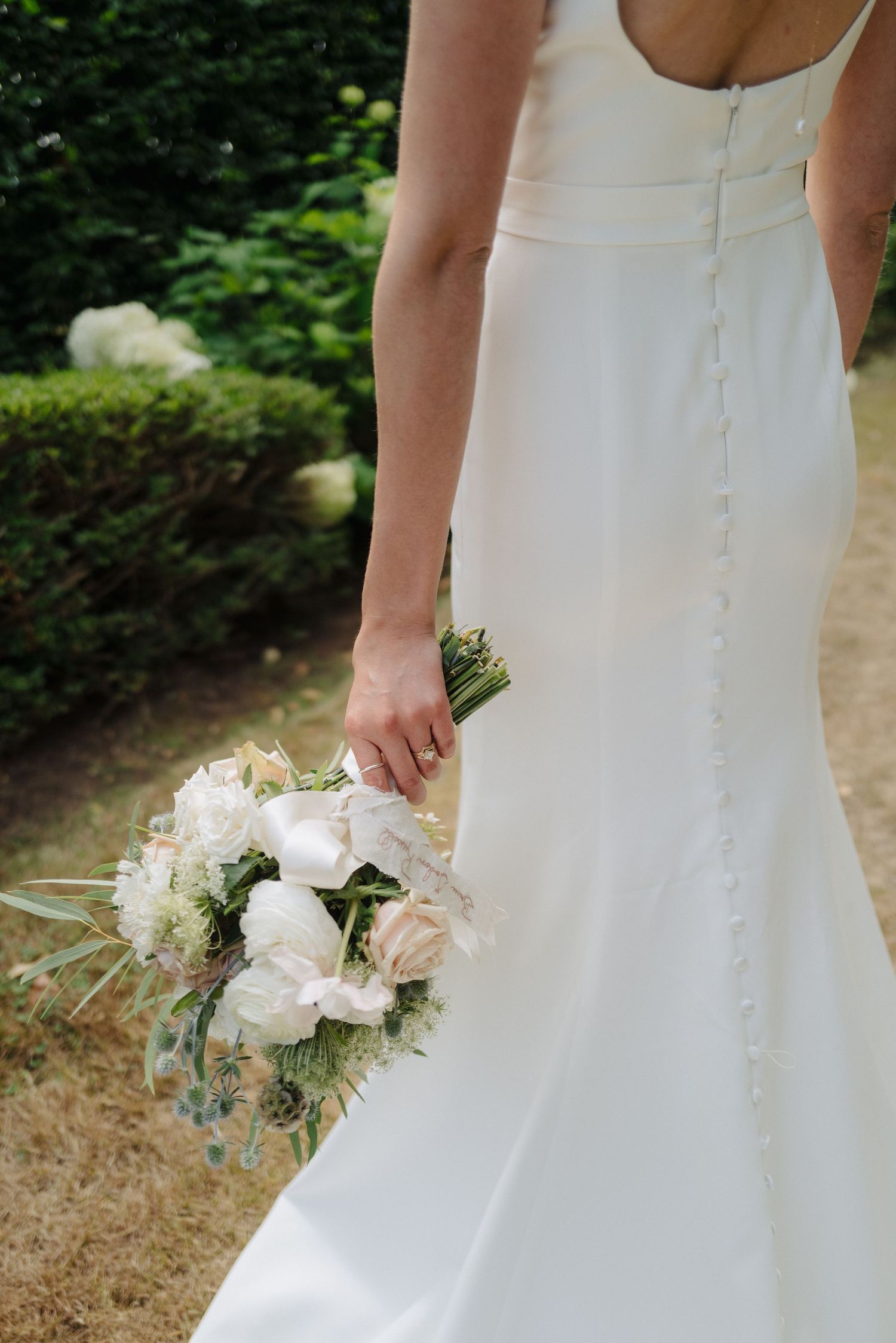 Detail shots of a white wedding dress with buttons and delicate bouquet.
