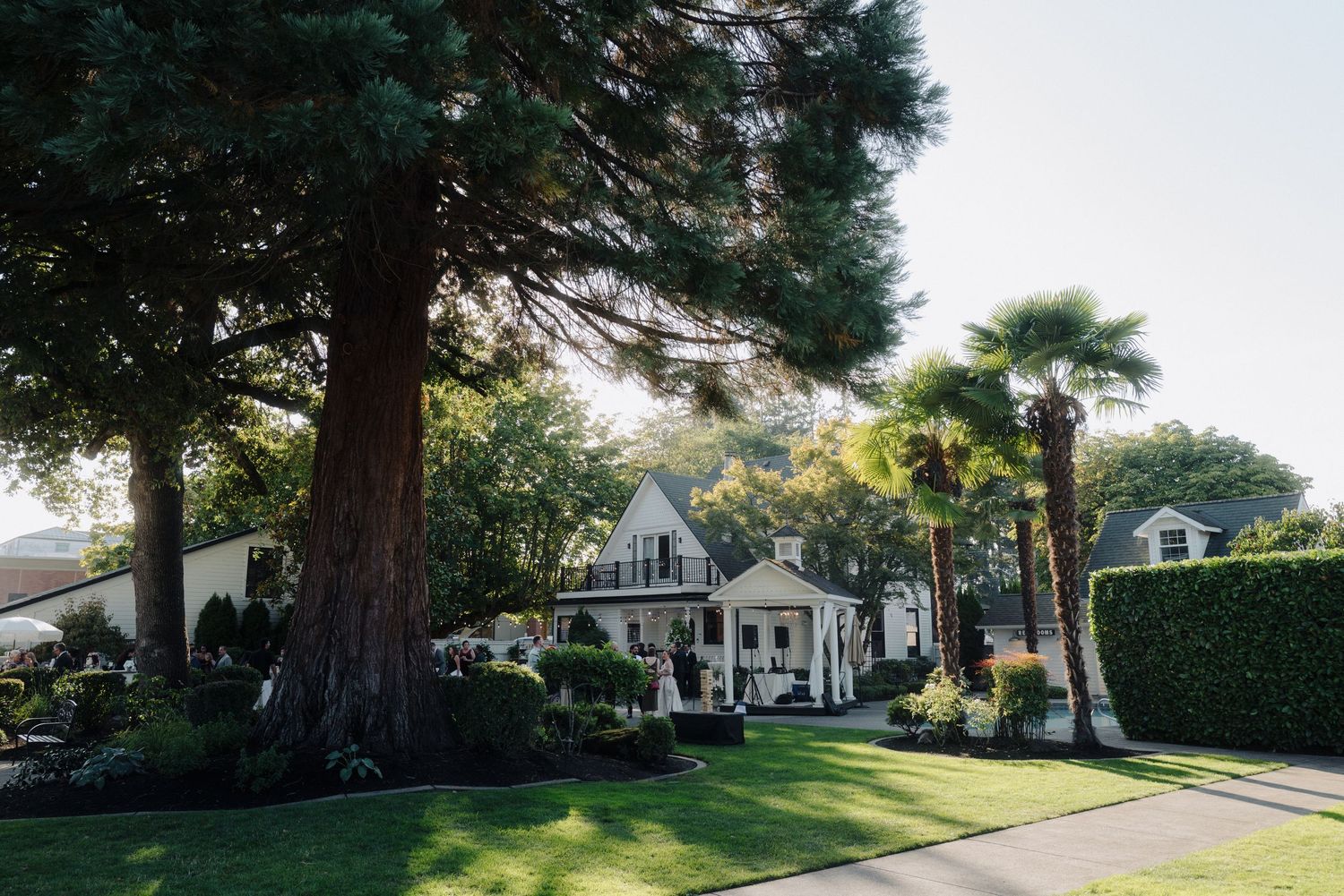 Beautiful white colonial style house with manicured lawn and tall trees.