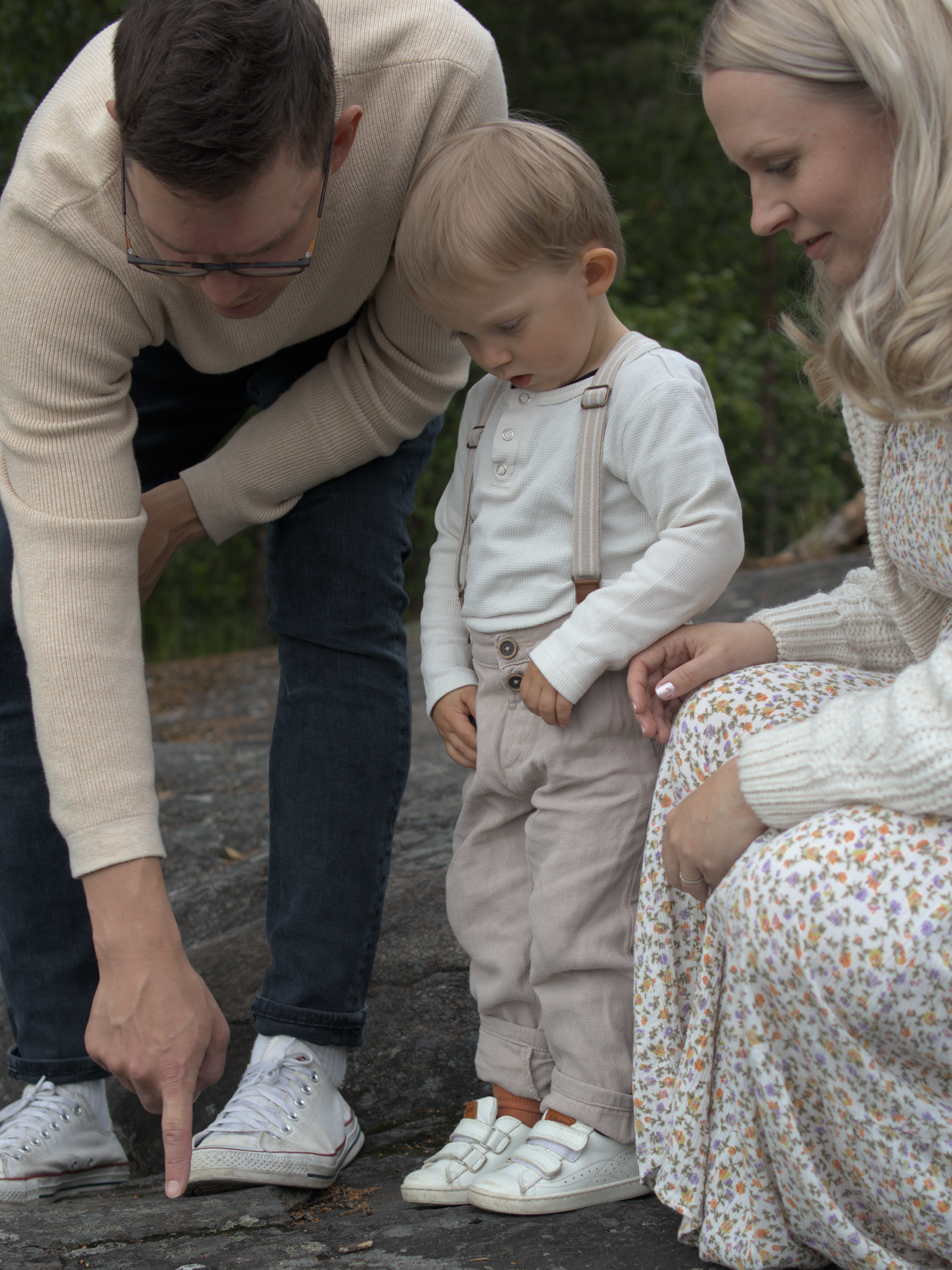 Perhe, johon kuuluu äiti, isä ja pieni lapsi, viettää yhteistä hetkeä kalliolla ihmetellen. Dokumentaarinen perhekuvaus pääkaupunkiseutu.