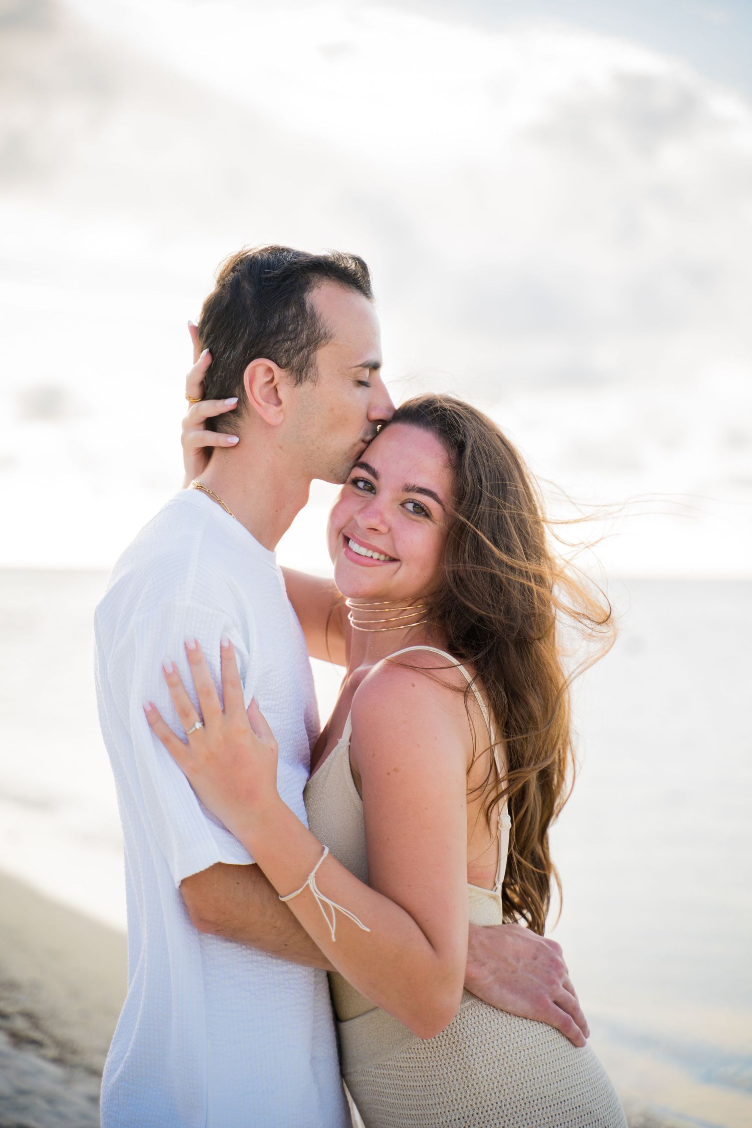 Romantic beach photoshoot capturing tender moments between couple at sunset.