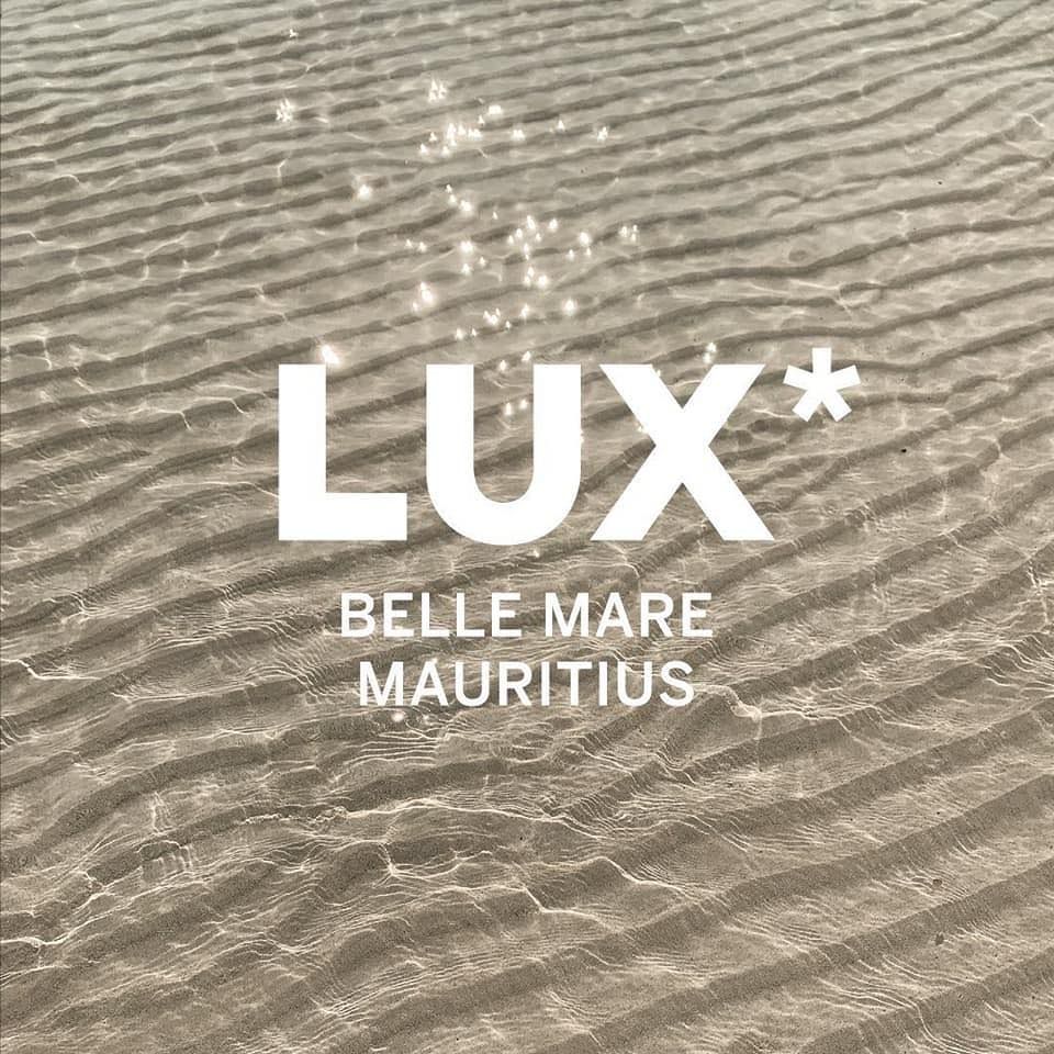 Logo design for LUX Belle Mare Mauritius resort with white text overlaid on a textured sand or water pattern background.