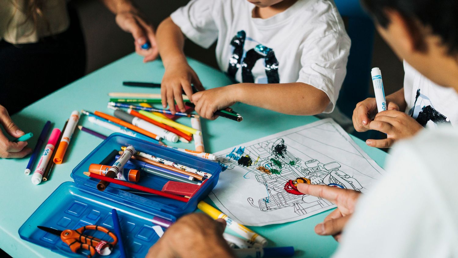 Close-up view of colorful toys and art supplies scattered on a blue table surface.