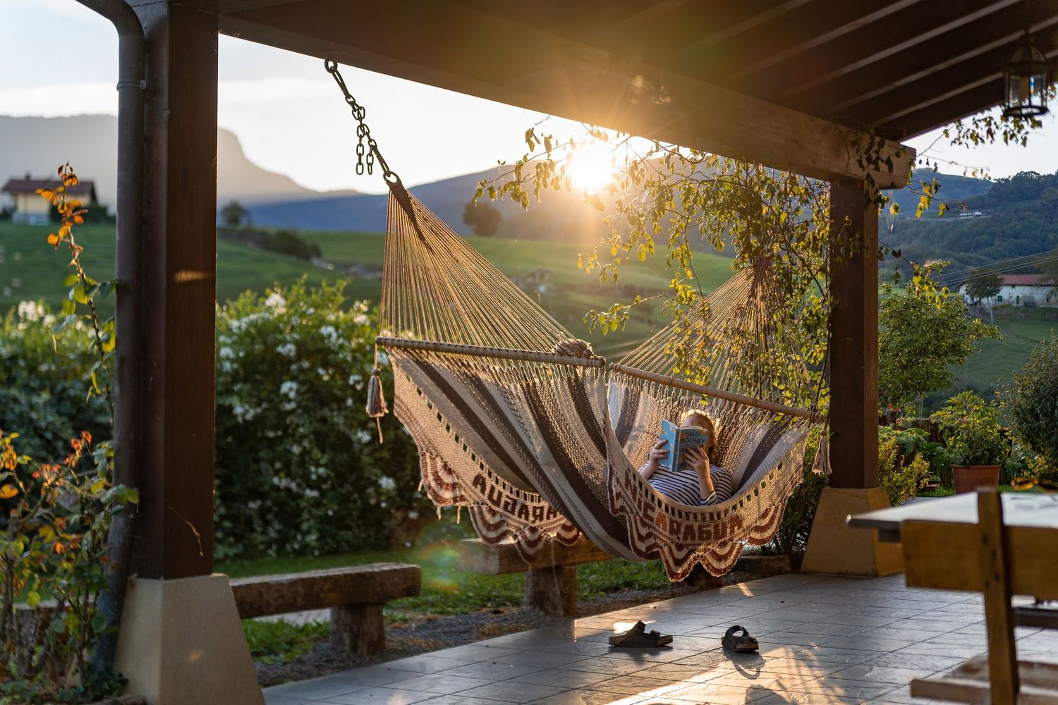 Hammock on porch overlooking scenic mountain valley at golden hour.
