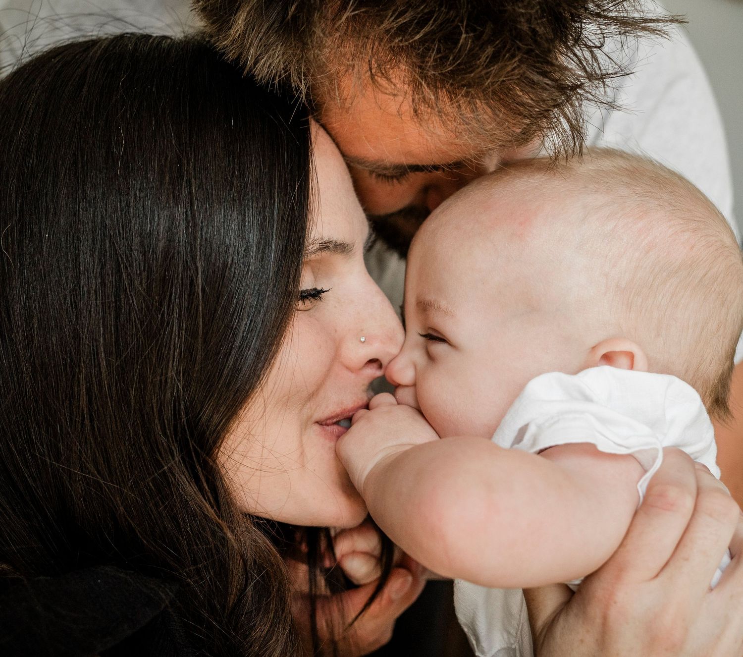 Close-up series of gentle kisses between parent and baby.