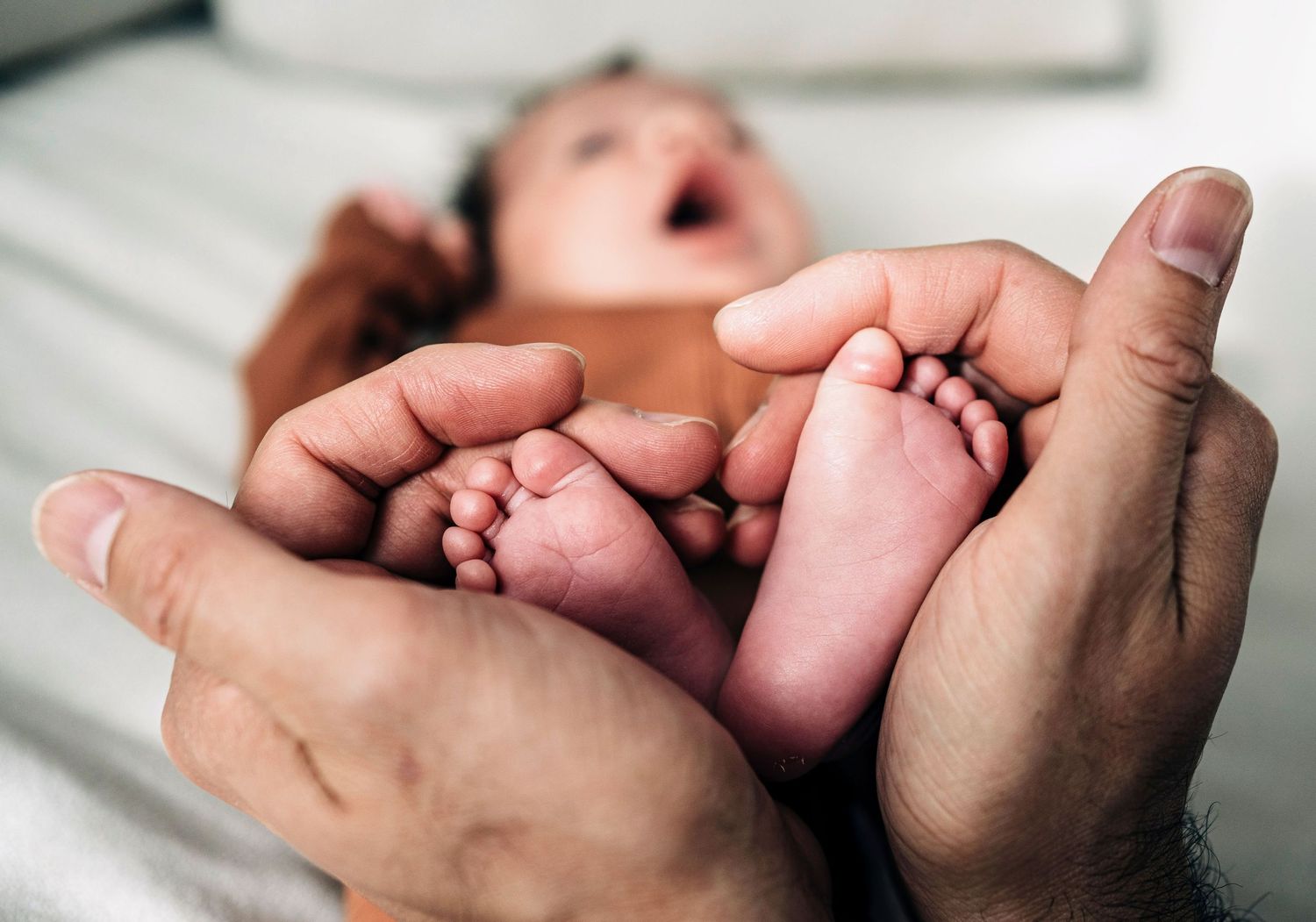 Close-up shots of tiny newborn feet being gently held by caring hands.