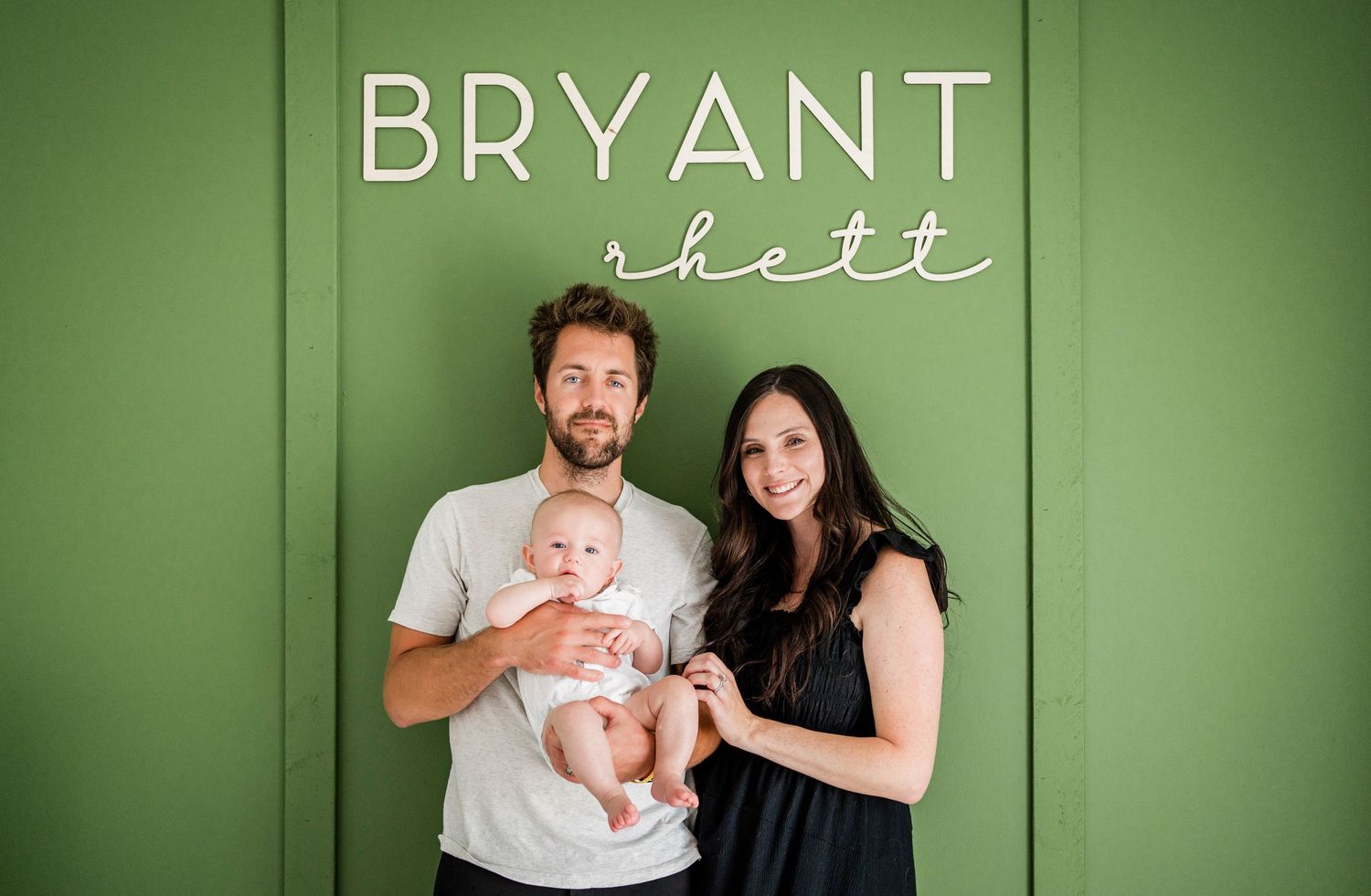 Family standing in front of nursery wall with the name of the baby.