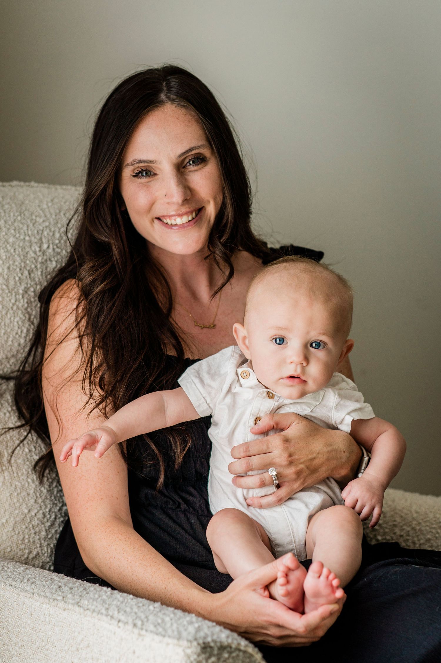 Lifestyle portraits showing joyful moments between mother and baby on light gray background.