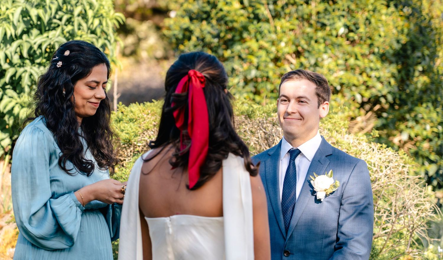 Wedding couple embraces outdoors in a beautiful garden with natural sunlight streaming through.