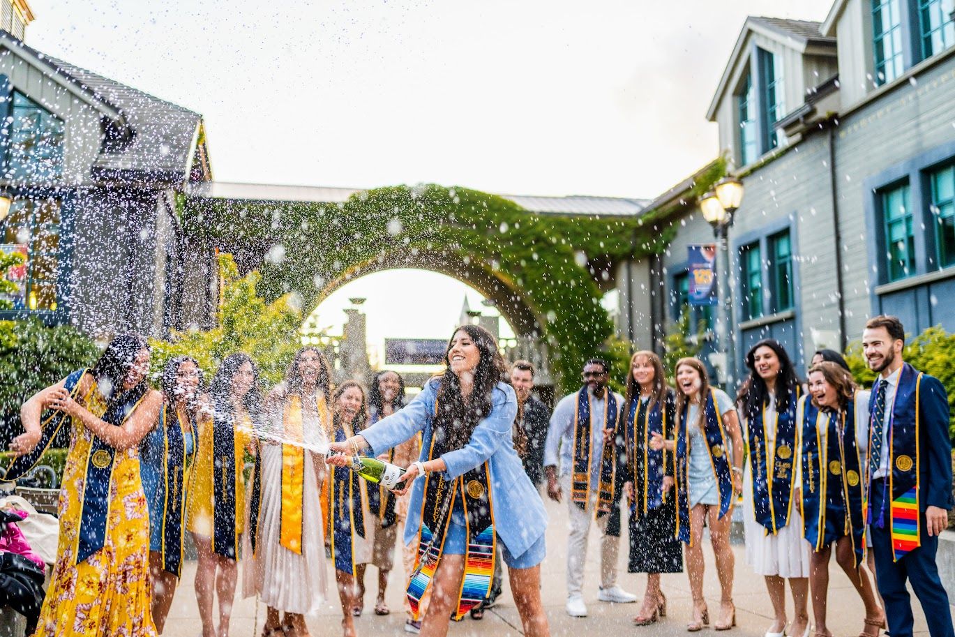 Festive college graduation celebration with champagne at sunset.