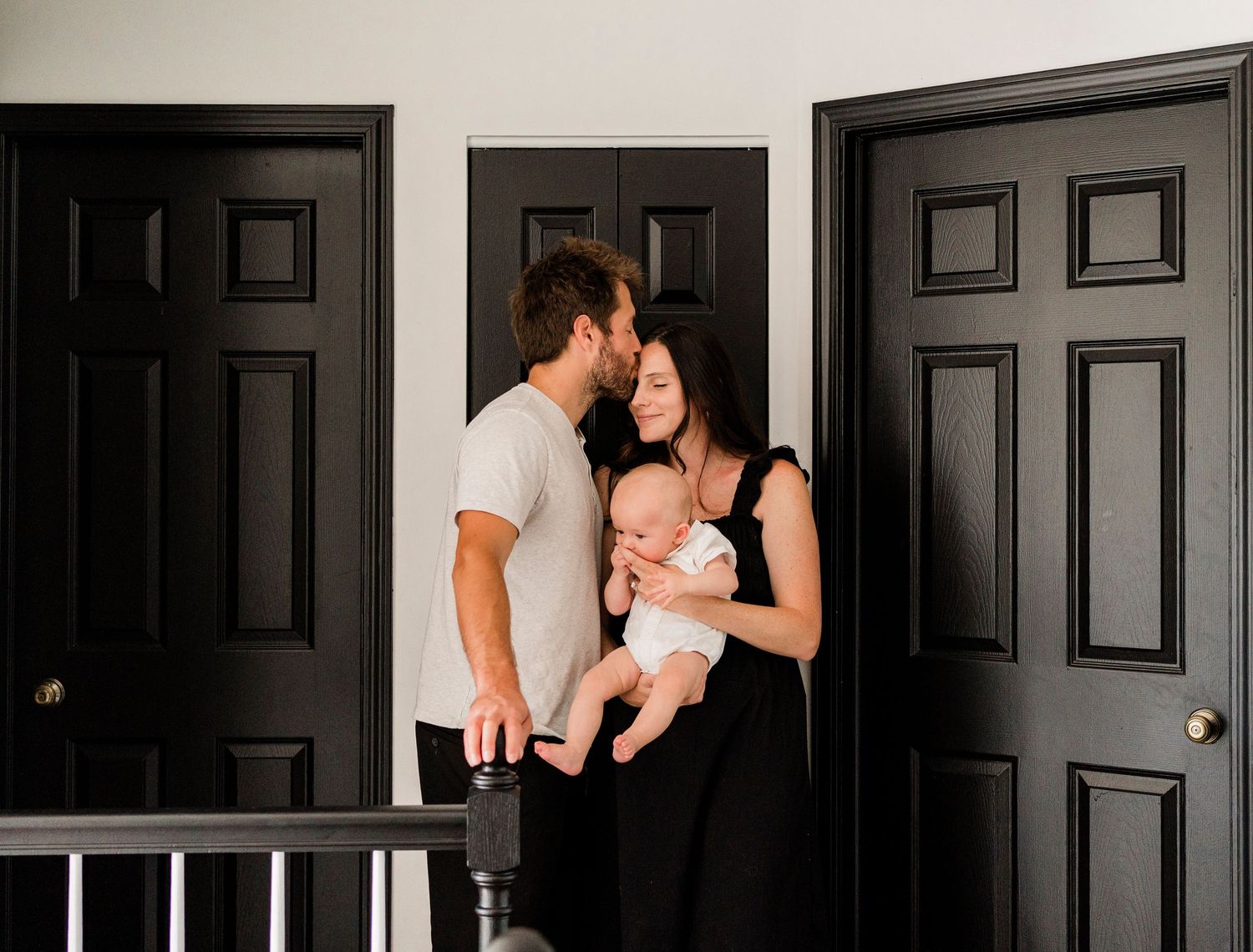 Series of candid family moments against black doors in a modern hallway.