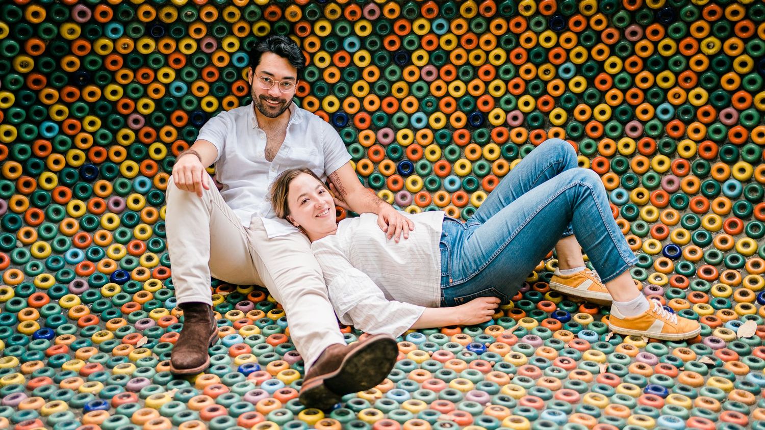 A couple relaxes on a colorful floor covered in orange and green circular patterns.