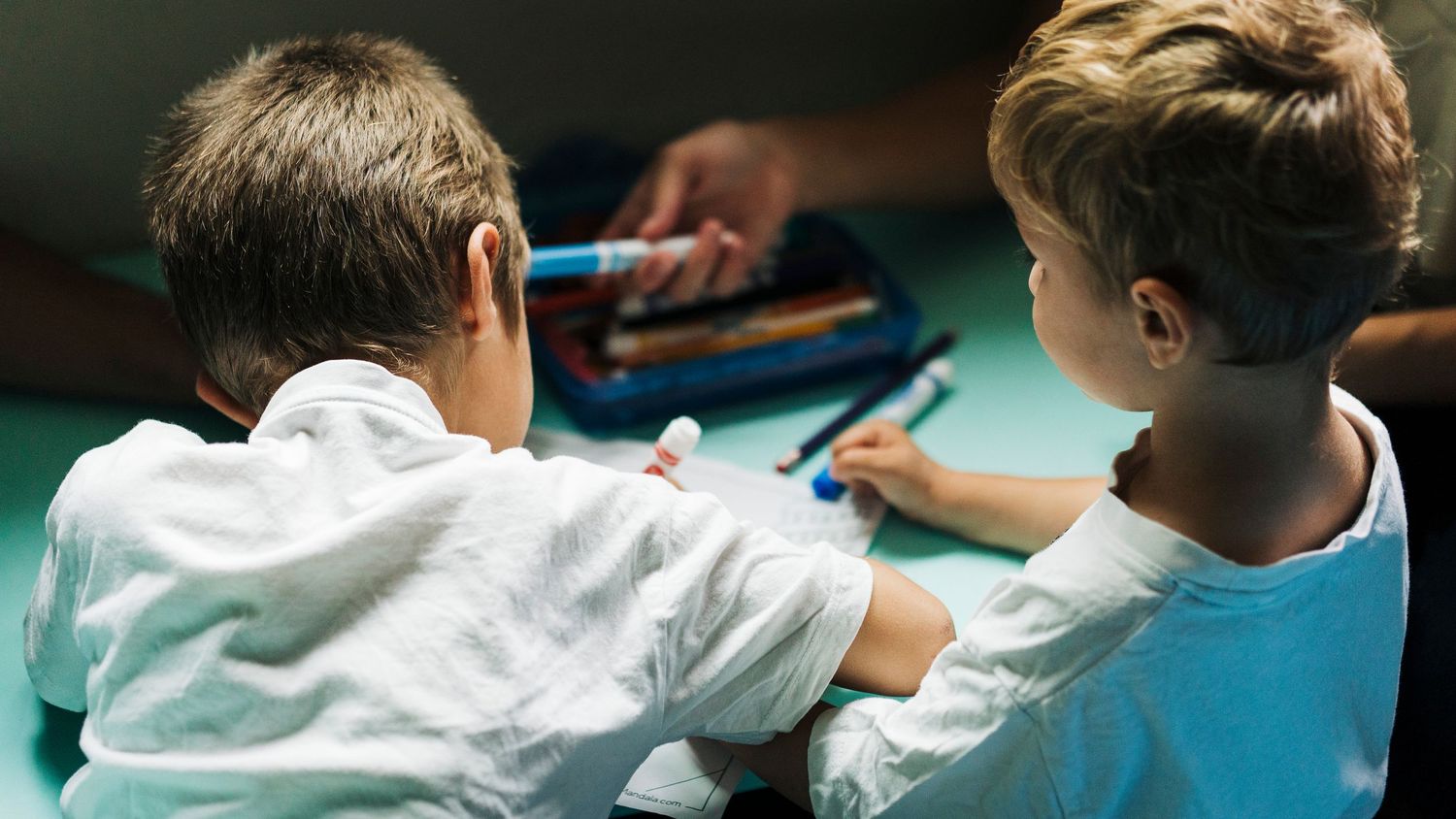 Students work together at tables in a classroom while engaging in hands-on learning activities.