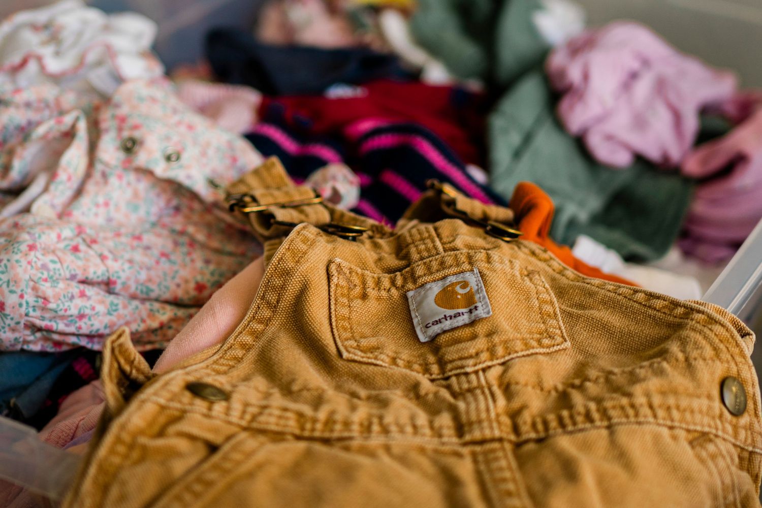 Close-up view of tan colored canvas overalls with metal buckles and stitching details on display.