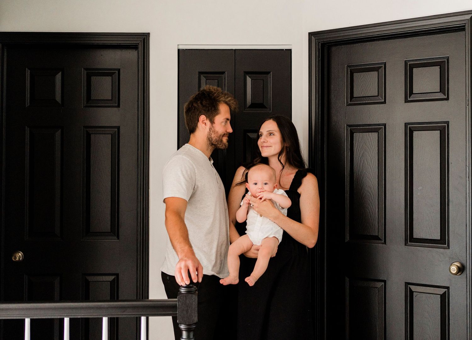 Family portrait sequence against black doors showing intimate moments of connection.