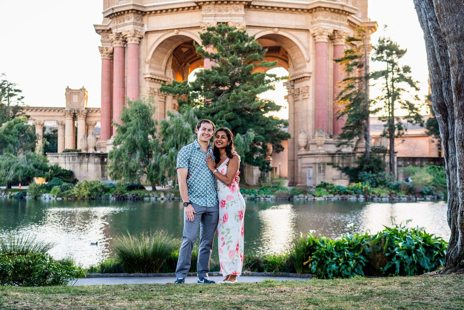 A couple poses for an engagement photo at the Palace of Fine Arts during golden hour.